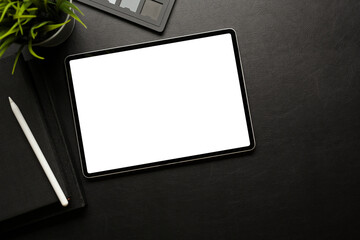 Dark workspace with digital tablet include clipping path screen, accessories and copy space