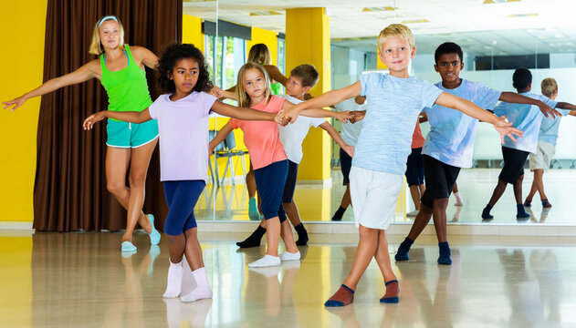 Preteen little active boys and girls dancing rock-and-roll in pairs in choreography class with female trainer © JackF