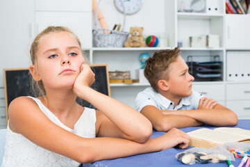 Sister is sitting offended because her brother is angry to her.
