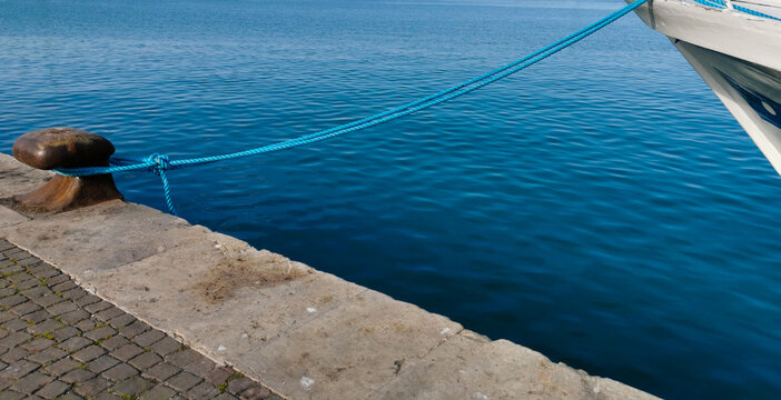 Bitta con gomena azzurra sul mare blu e barca bianca attraccata