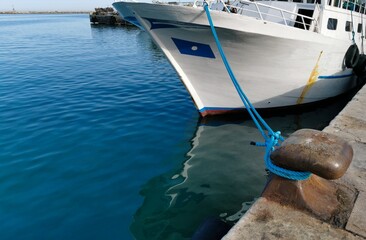 Bitta con gomena azzurra sul mare blu e barca bianca attraccata