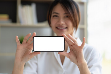 Smiling beautiful asian businesswoman showing blank smartphone monitor, with copyspace area for slogan or text message.