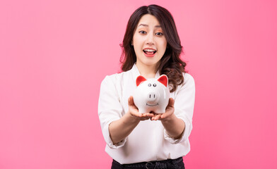 Fototapeta na wymiar Asian businesswoman holding piggy in her hand, saving money concept