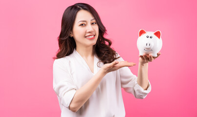 Fototapeta na wymiar Asian businesswoman holding piggy in her hand, saving money concept