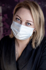 Portrait of a manicure master in the workplace in a mask. Manicurist in black jacket, protective mask and gloves at the workplace waiting for the client. Selective focusing. 