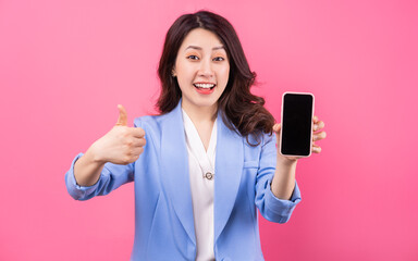 Fototapeta premium Asian businesswoman using smartphone on pink background