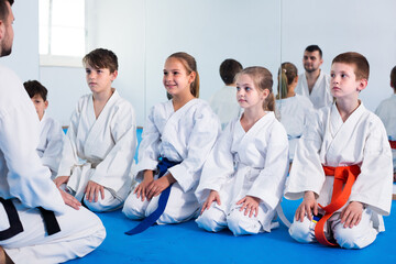 Fototapeta na wymiar Smiling kids sparring in pairs to practice new moves in karate class
