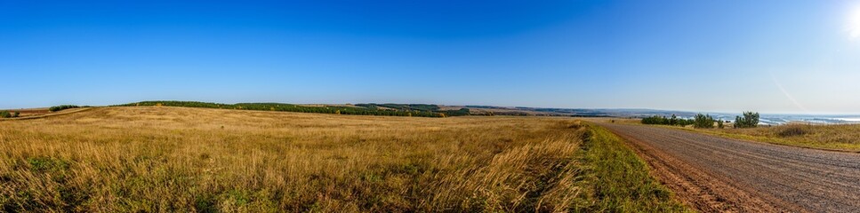Obraz premium Panorama of the landscape with a dirt road going into the distance. In the background, the Kama River. Karakulinsky district. Udmurt Republic, Russia.
