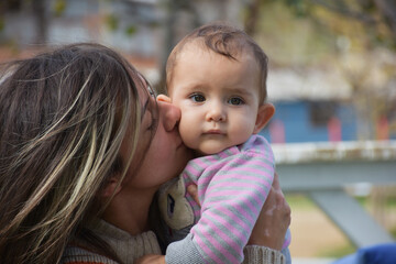 a happy mother kissing her baby lovingly