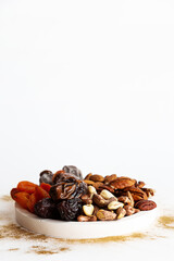 Various nuts and dried fruits, on a white-gold background. Vegan and vegetarian concept, healthy source of fat. Healthy snack assortment