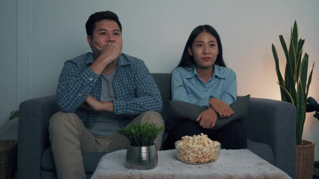 Asian couple sit and win their favorite teams broadcasting live football matches.