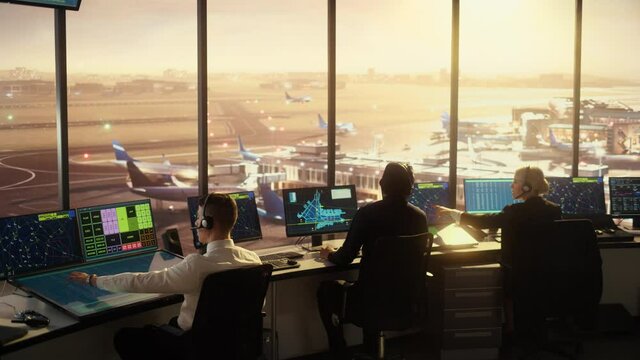 Diverse Air Traffic Control Team Working in a Modern Airport Tower at Sunset. Office Room is Full of Desktop Computer Displays with Navigation Screens, Airplane Flight Radar Data for Controllers.