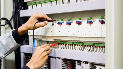 Electrical engineer tests the operation of the electric control cabinet on a regular basis for maintenance.