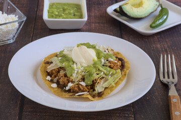 Traditional Mexican food. Picadillo toast with guacamole, sour cream, lettuce and cheese, accompanied by avocado slices.
