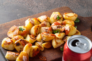 Popular Spanish tapa, Patatas bravas on wooden cut board and dressing with  tomato sauce and aioli