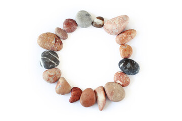 Round frame made of stones on a white background, pebbles laid out in a circle, copy space in the center