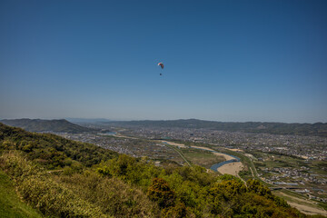 Fototapeta na wymiar 快晴の空の下を飛ぶパラグライダー。和歌山県紀の川市、寺山スカイスポーツから撮影