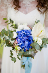 Bride holds wedding bouquet with hydrangea, eucalyptus, calla and eustoma