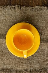 Top view of empty yellow cup and saucer on wooden rustic bckground. Kitchen crockery