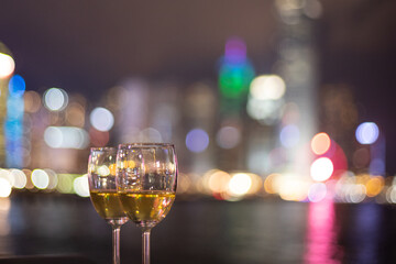 two glasses wine with twinkling blurred city night lights in Central, Hong Kong Victoria Harbour as background, romantic concept for lovers and valentine
