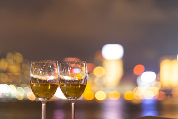 two glasses wine with twinkling blurred city night lights in Central, Hong Kong Victoria Harbour as background, romantic concept for lovers and valentine