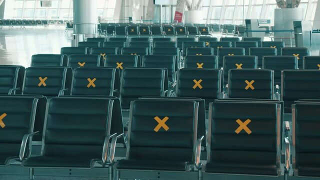Seats at the airport marked for social distancing. Empty airport terminal, no people. Pandemic, covid-19 lockdown concept.