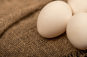 Three white chicken eggs on a rough-textured homespun cloth.