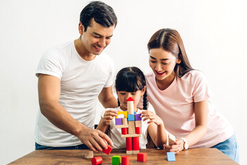 Portrait of enjoy happy love asian family father and mother with little asian girl smiling playing with toy build wooden block board game in moments good time at home