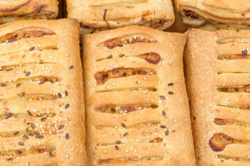 Strudel stuffed with ham and cheese. View top. Radiator-shaped strudel notches. Sesame and flax seeds.