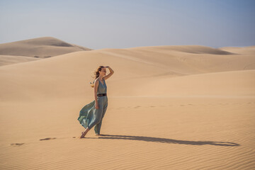 Young beautiful woman traveling in the desert. Sandy dunes and blue sky on sunny summer day. Travel, adventure, freedom concept. Tourism reopens after quarantine COVID 19