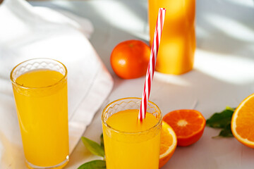 Glass of orange juice with red straw on table