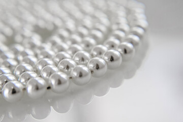 A necklace of pearls lying on white glass