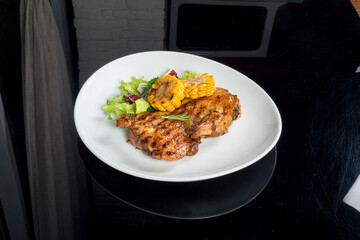Meat with corn and fresh herbs on a white plate