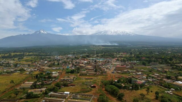 Aerial view over a African village, forest fire background - reverse, drone shot