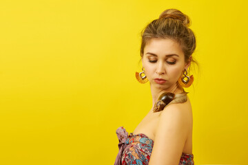 Beautiful young woman with a snail on her body on a yellow background, cosmetology procedure