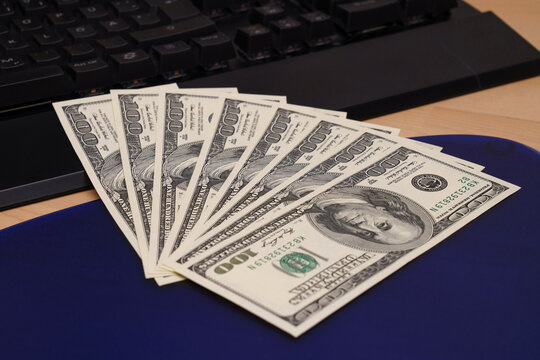 One Hundred Dollar Bills Fanned Out On A Computer Keyboard.