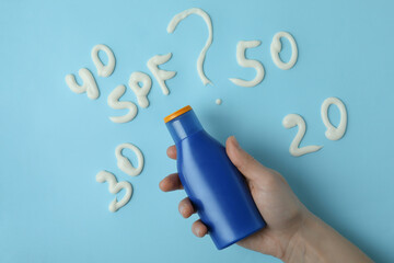 Female hand holds sunscreen on blue background with text SPF?