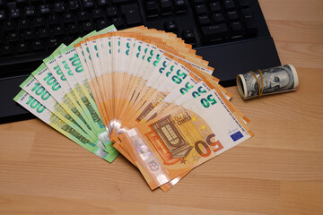 One hundred and fifty euro bills on the keyboard. Near a roll of one hundred dollars.