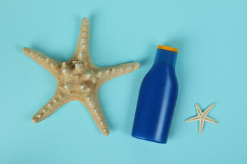 Blue bottle of sunscreen and starfishes on blue background