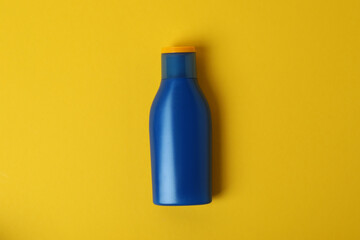 Blue bottle of sunscreen on yellow background