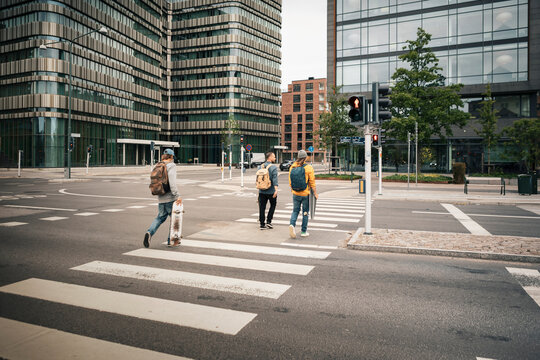 Rear view of male friends crossing street in city