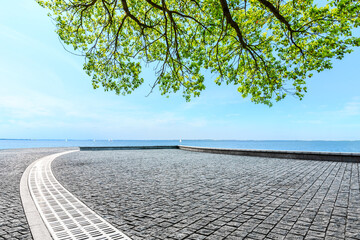 Fototapeta na wymiar Empty square floor and green tree with lake landscape under the blue sky.