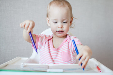 A little girl tries to draw with felt-tip pens with pleasure and interest. High quality photo