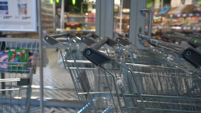 Take a Grocery Cart for Shopping. Close-up Male Hand Shopper Pulling Shopping Cart from Row in Supermarket or Grocery Store