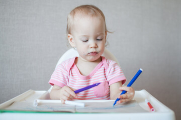 A little girl tries to draw with felt-tip pens with pleasure and interest. High quality photo