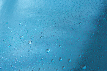 Abstract blue background with raindrops and beautiful bokeh. The concept of autumn and the cold stormy weather. Texture of macro drops on the blurred background of the window. Loneliness sadness