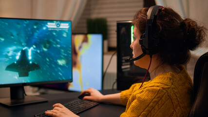 Professional esport woman gamer using mic of headset talking playing shooter game with team on streaming services. Virtual shooter game in cyberspace, esports player performing on pc gaming tournament © DC Studio