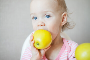 Fototapeta na wymiar A little girl tastes, examines and plays with fresh apples with pleasure and interest. High quality photo