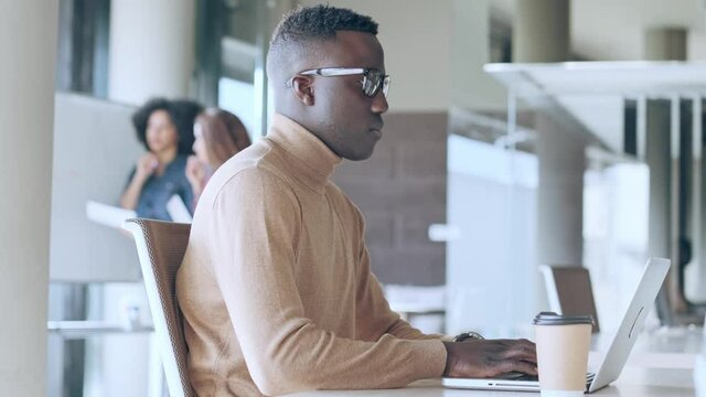 Video of concentrated black business man working with laptop in the office on coworking place.