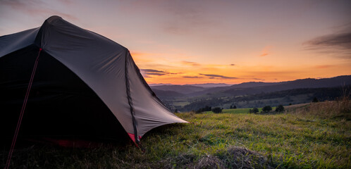 Tourist tent in the mountains under dramatic evening sky. Colorfull sunset in mountains. Camping travell concept. Traveler people enjoying the advanture alternative vacation © Zedspider